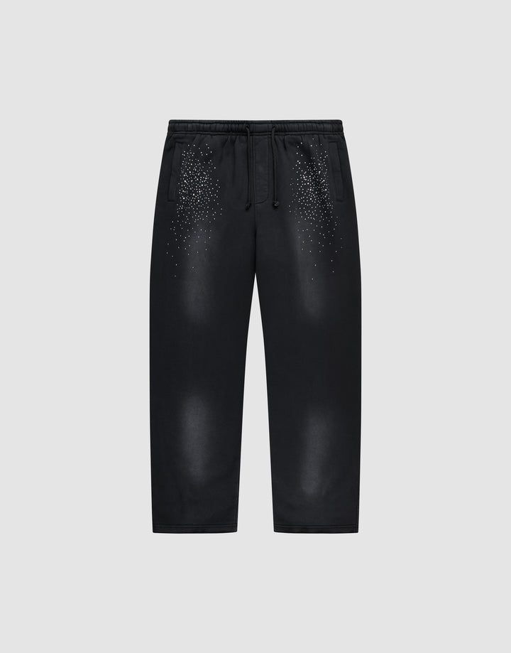 The LIVE FAST DIE YOUNG Live Fast Rhinestone Jogger is a black sweatpant with an elastic waistband and drawstrings, featuring a spray effect gradient and scattered small white dots on the upper front. Shown on a plain light gray background. | plain