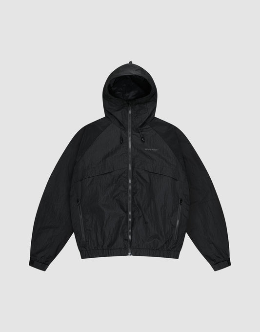 The LIVE FAST DIE YOUNG Live Fast Nylon Jacket is a black, oversized zip-up windbreaker with long sleeves, hood, Stehkragen, and side pockets, shown against a plain light gray background. | plain
