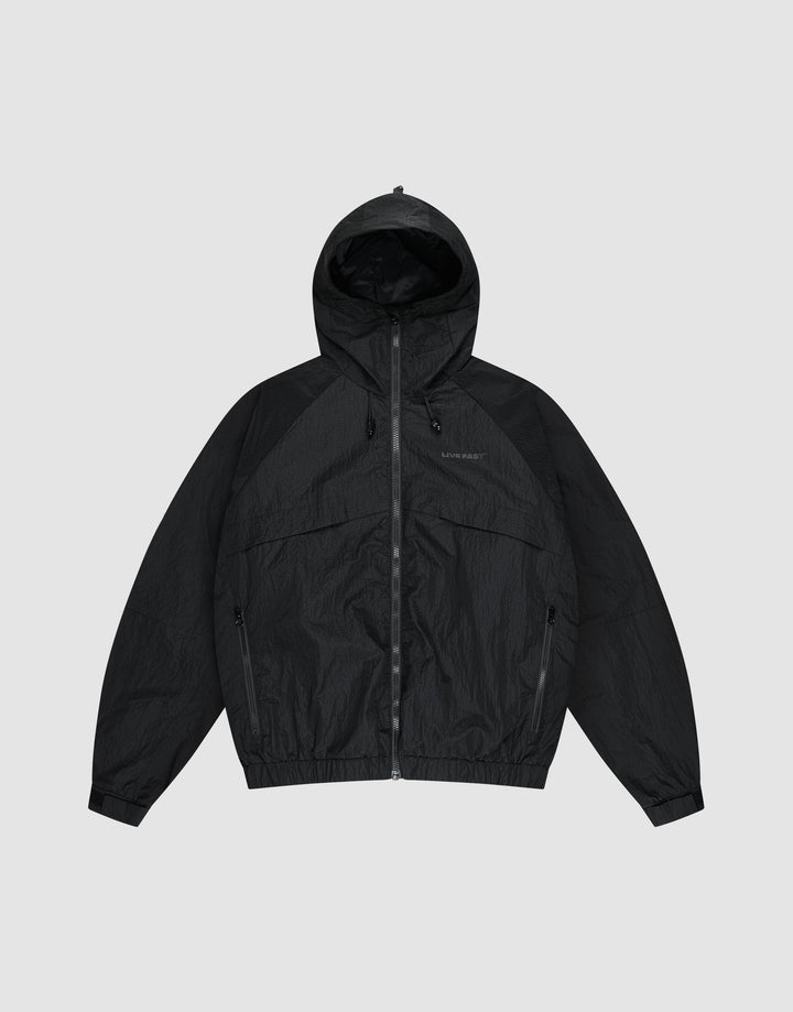 The LIVE FAST DIE YOUNG Live Fast Nylon Jacket is a black, oversized zip-up windbreaker with long sleeves, hood, Stehkragen, and side pockets, shown against a plain light gray background. | plain