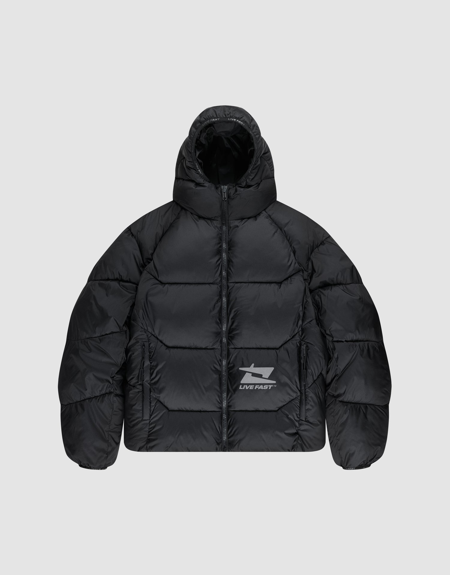The Live Fast Puffer Jacket by LIVE FAST DIE YOUNG is a black, water-repellent jacket with a hood, front zipper, and reflective "LIVE FAST" text plus a shark graphic on the left chest. Seen here on a light gray background. | plain