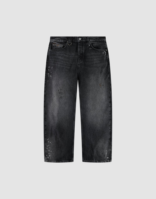The LIVE FAST DIE YOUNG LFDY Baggy Denim is a pair of black jeans with a wide straight leg, baggy fit, faded wash, and white paint splatters, shown on a plain light gray background. | plain