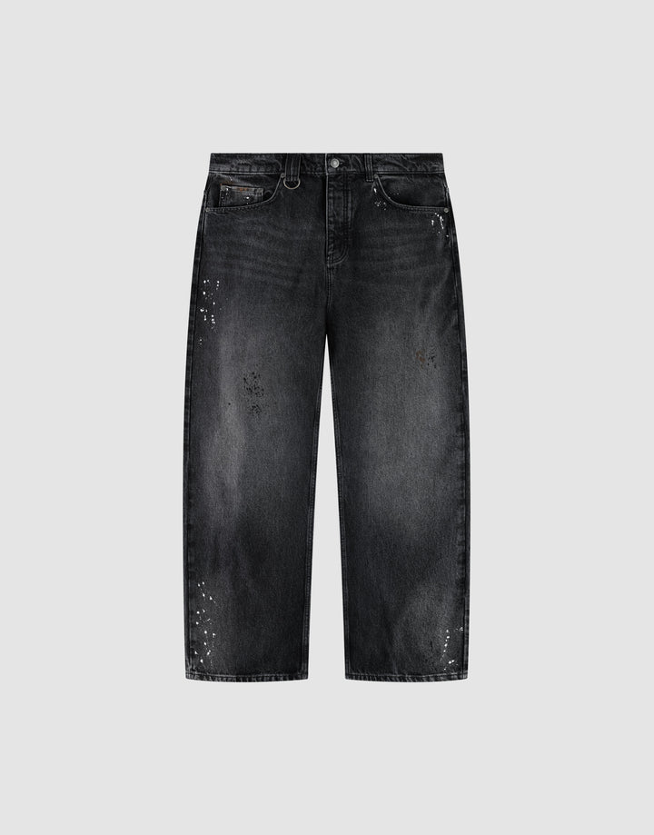 The LIVE FAST DIE YOUNG LFDY Baggy Denim is a pair of black jeans with a wide straight leg, baggy fit, faded wash, and white paint splatters, shown on a plain light gray background. | plain