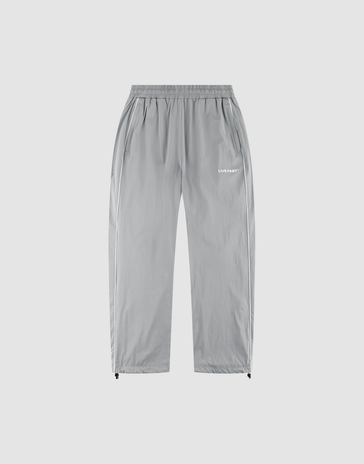 The LFDY Ripstop Trackpants by LIVE FAST DIE YOUNG feature light gray nylon, a wide elastic waistband, side pockets, adjustable ankle drawstrings, and a white "LUV IS RAGE" silicone logo on the upper left thigh for a modern look. | plain
