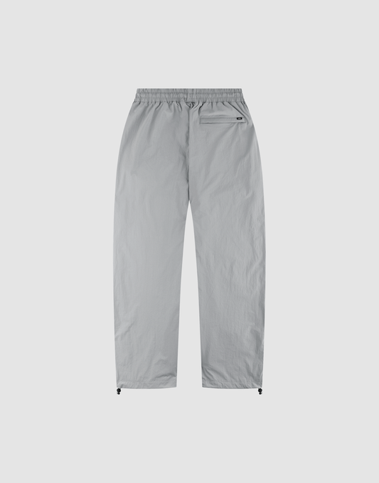 The LIVE FAST DIE YOUNG LFDY Ripstop Trackpants in light grey feature a wide elastic waistband, straight legs, a zippered back-right pocket, and adjustable ankle drawstrings—shown laid flat on a plain white background.
