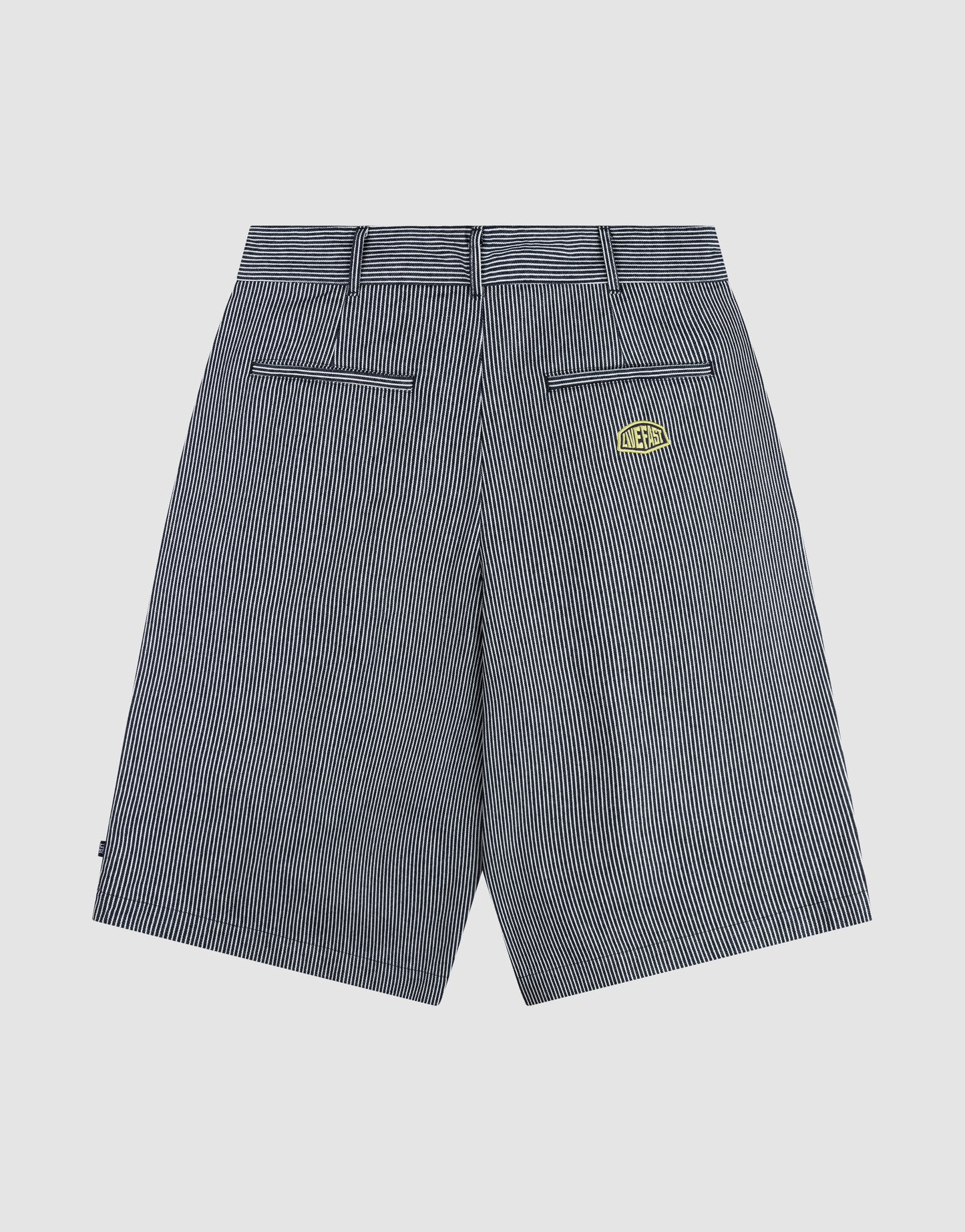 Back view of LFDY Twill Shorts by LIVE FAST DIE YOUNG in black and white pinstripes, featuring wide straight legs, belt loops, two back welt pockets, a yellow-black logo patch above the right pocket, and crafted from 100% cotton for comfort and style.