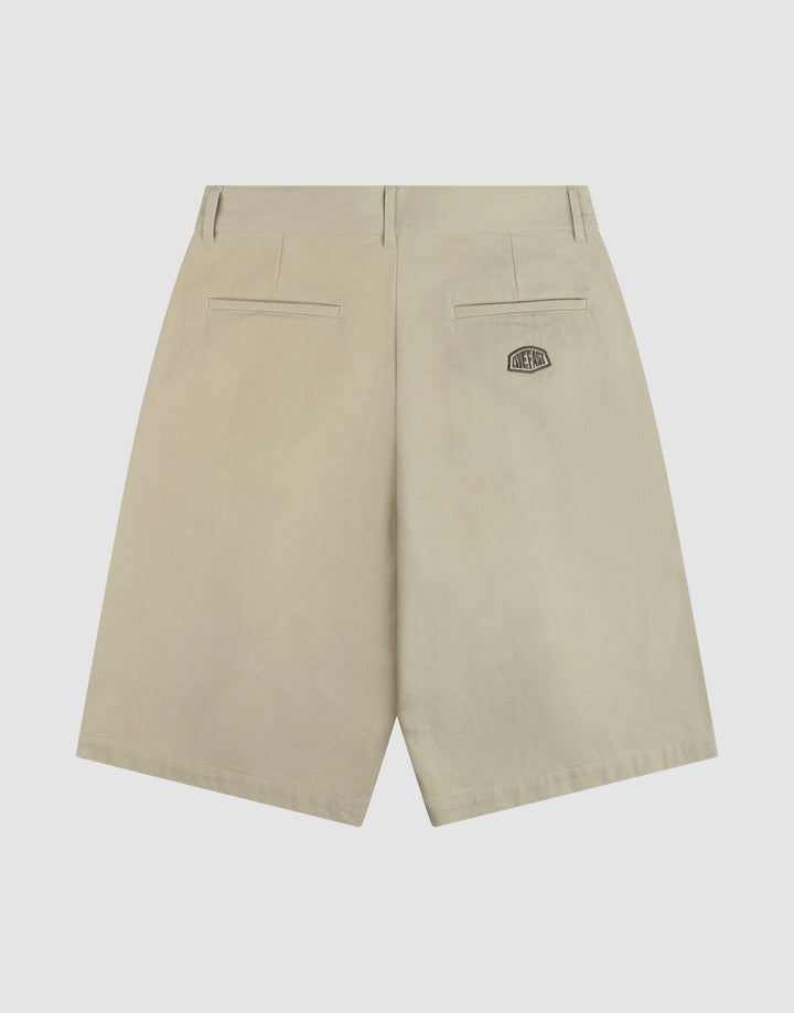 The LFDY Twill Shorts by LIVE FAST DIE YOUNG are beige cotton shorts with an oversize fit, wide straight leg, two back welt pockets, and a small black patch with white text above the right pocket for a relaxed look.