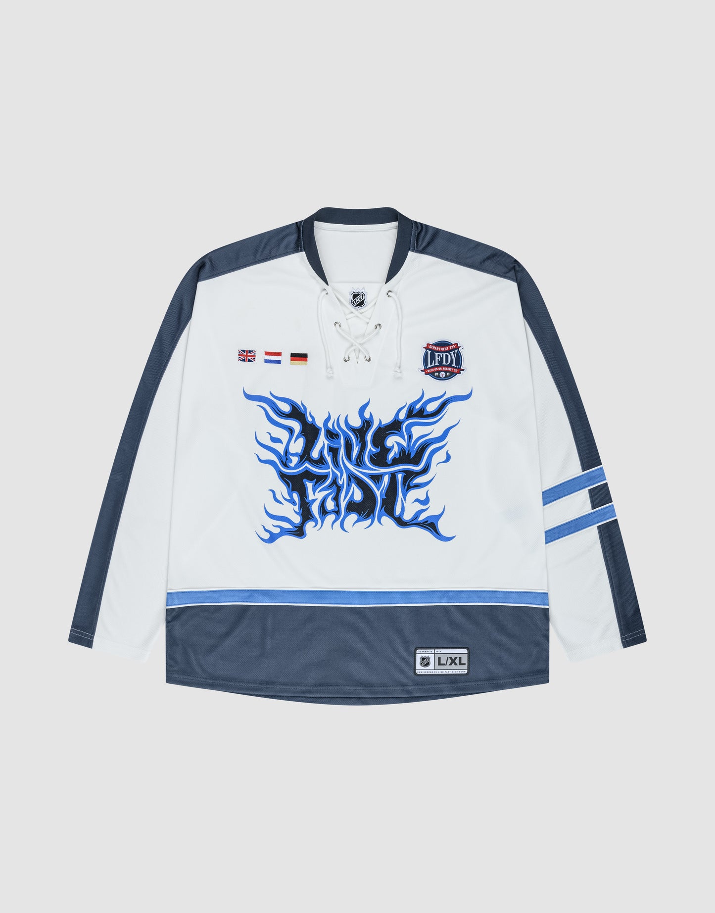 The LFDY Flames Jersey by LIVE FAST DIE YOUNG is a white and navy oversized hockey jersey with a lace-up collar, blue flame graphic, stick patches, small flags, LPDY chest patch, and striped sleeves and hem.