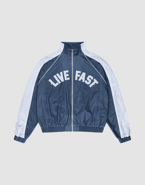 The LFDY Arch Trackjacket by LIVE FAST DIE YOUNG is a blue and white zip-up jacket with an oversize fit, featuring "LIVE FAST" in bold white letters across the chest and seitliche Eingrifftaschen for convenience. | plain