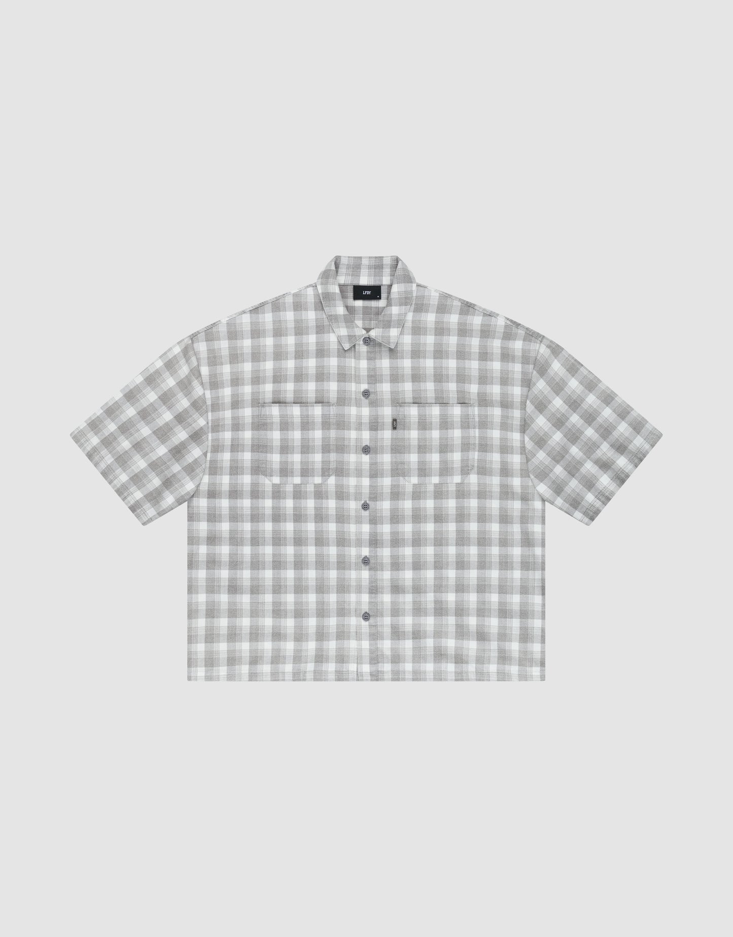 The LIVE FAST DIE YOUNG LFDY Light Flannel is an oversize fit, short-sleeved button-up with gray and white plaid, two chest pockets, and a pointed collar, shown on a plain light background.