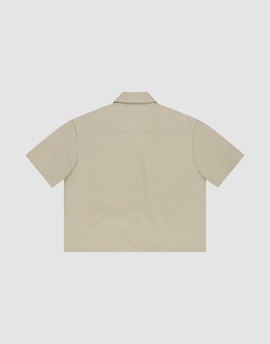 The LFDY Twill Shirt by LIVE FAST DIE YOUNG is a beige, short-sleeve shirt made from 100% Baumwolle, shown flat from the back with a classic collar and straight hem against a white background.