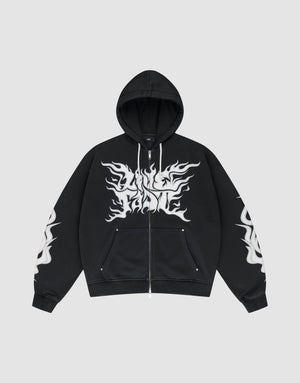 The LIVE FAST DIE YOUNG LFDY Inferno Hooded Zip is a black oversized zip-up hoodie with drawstring hood and front pockets, featuring bold white flame graphics on chest and sleeves, shown against a plain gray background. | plain