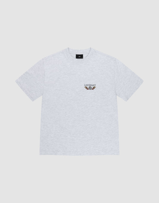 The LFDY Under Fire Tee by LIVE FAST DIE YOUNG is a light grey oversized cotton t-shirt with a small "LIVE FAST" text and winged wheel graphic on the left chest, shown flat on a white background.