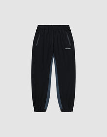 Black Basic Shell Pants by LIVE FAST DIE YOUNG with elastic waistband, zippered side pockets, gray panels, and elastic cuffs. Features a white reflective logo on the left thigh. Displayed on a plain light background. | plain