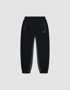 Black Basic Shell Pants by LIVE FAST DIE YOUNG with elastic waistband, zippered side pockets, gray panels, and elastic cuffs. Features a white reflective logo on the left thigh. Displayed on a plain light background. | plain