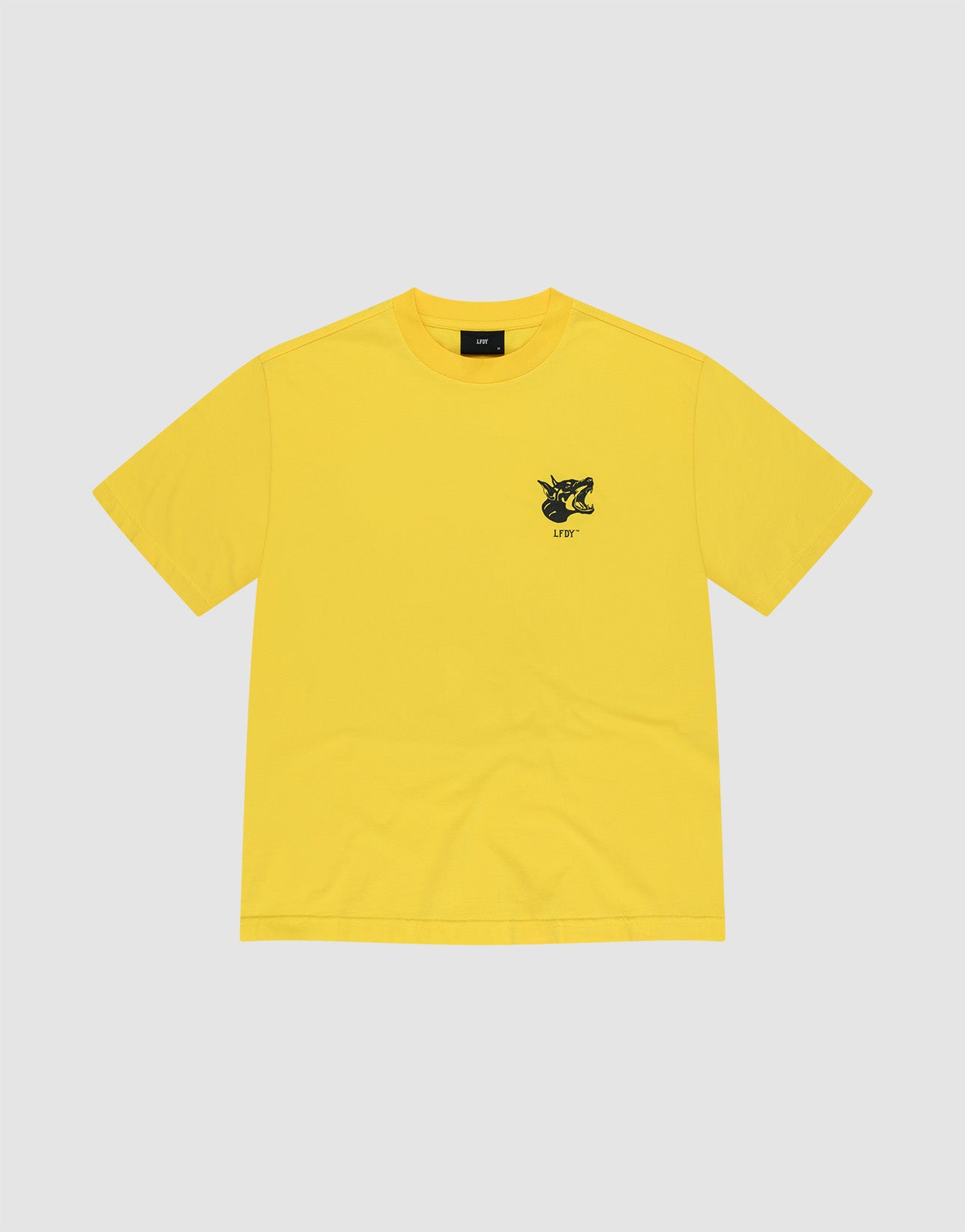 The LFDY Circle Dog Tee by LIVE FAST DIE YOUNG is a plain yellow oversized short-sleeve t-shirt with a small black and yellow "LIVIN" graphic on the left chest, shown on a light gray background.