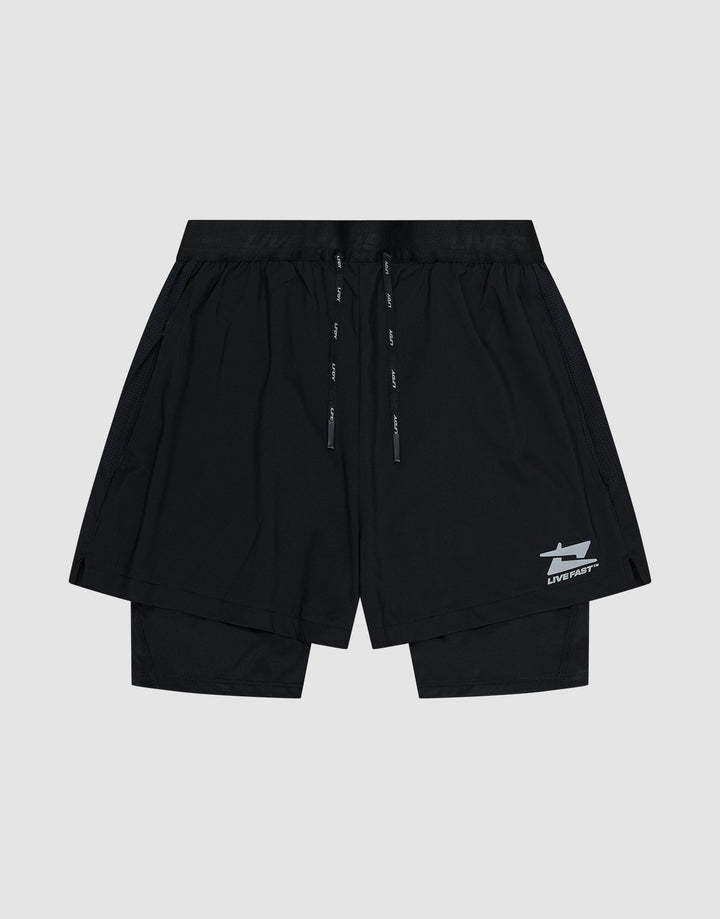 The LIVE FAST DIE YOUNG Live Fast Performance Running Shorts feature an overlapping design with built-in tights, elastic waistband with drawstrings, and a small white Live Fast Branding logo on the lower left leg, shown on a plain light gray background.| plain