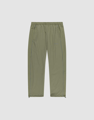 The Live Fast Trackpants by LIVE FAST DIE YOUNG are light olive green, wide-fit, lightweight pants with an elastic waistband, side pockets, subtle seam details, ankle zippers, and a reflective logo print. Shown on a plain white background. | plain
