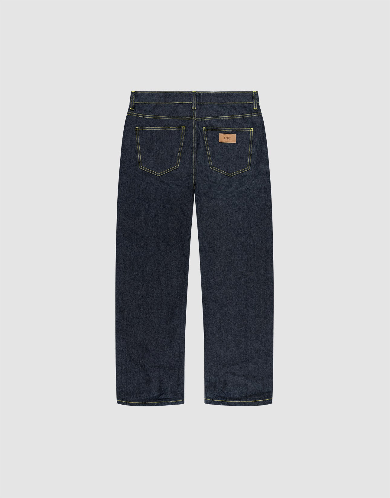 The LIVE FAST DIE YOUNG Work Denim jeans feature a straight-leg cut in dark blue raw denim, two rear pockets with yellow stitching, and a brown leather waistband patch, shown from the back.