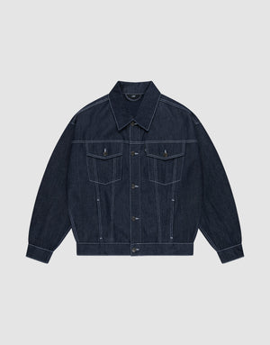 Die LFDY Denim Jacket von LIVE FAST DIE YOUNG aus 100% Baumwolle präsentiert sich in dunklem Raw-Denim mit spitzem Kragen, Knopfleiste, Brusttaschen mit Klappen und weißen Kontrastnähten auf hellgrauem Hintergrund. | plain
