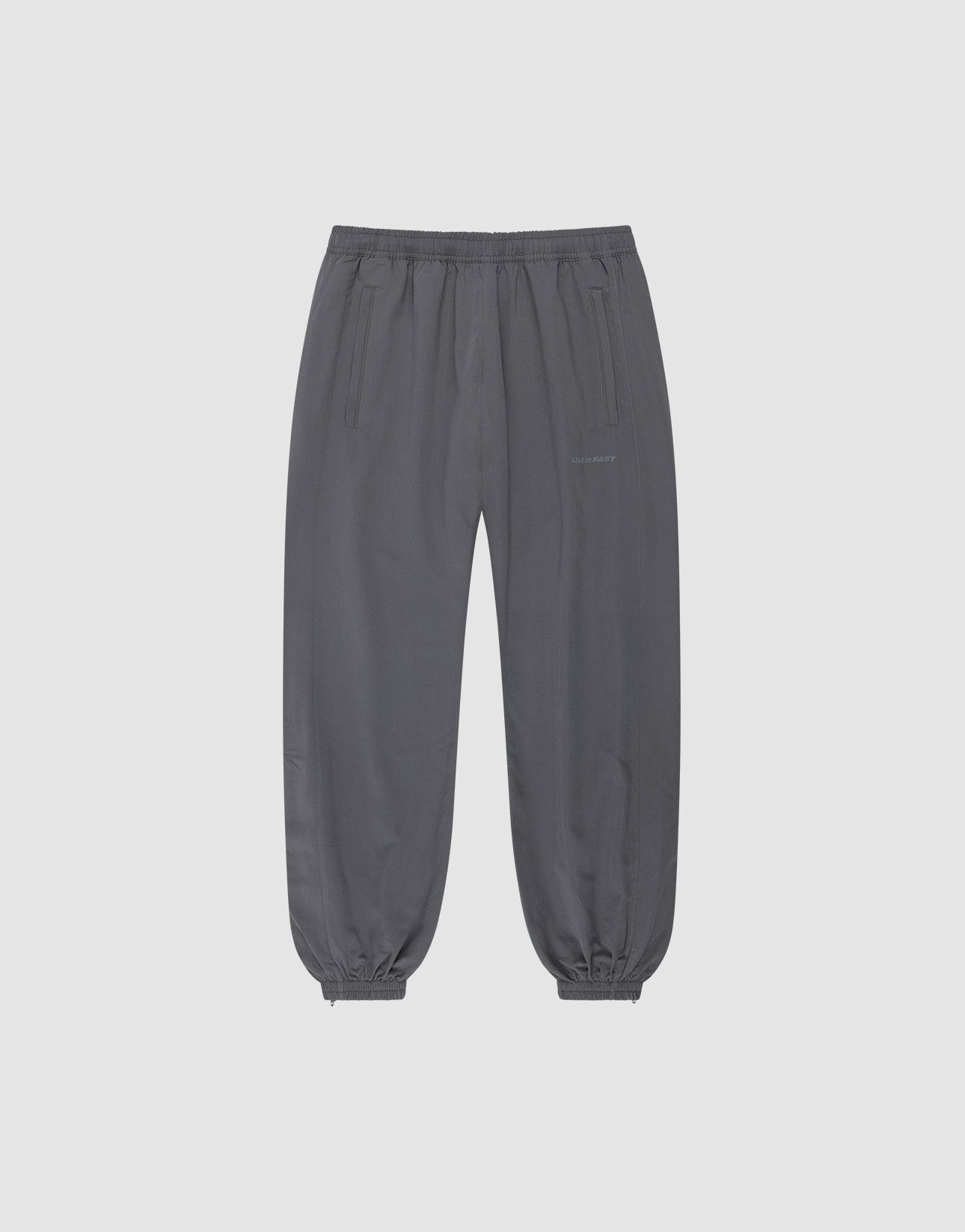 The LFDY Trackpants by LIVE FAST DIE YOUNG are dark gray joggers in a regular fit with an elastic waistband, cuffs, side pockets, polyester blend fabric, and subtle reflektierender Druck detail, shown on a plain light gray background.