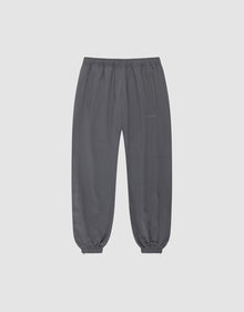 The LFDY Trackpants by LIVE FAST DIE YOUNG are dark gray joggers in a regular fit with an elastic waistband, cuffs, side pockets, polyester blend fabric, and subtle reflektierender Druck detail, shown on a plain light gray background. | plain