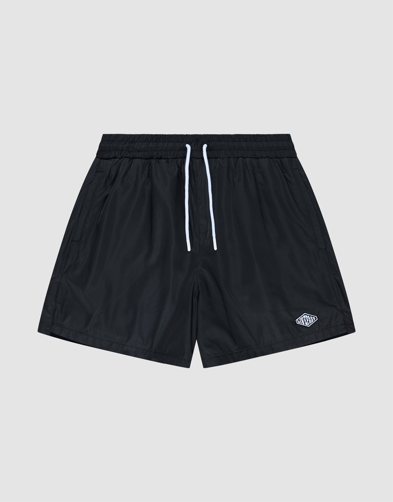 The Basic Satin Shorts by LIVE FAST DIE YOUNG are black polyester athletic shorts with an elastic waistband, white drawstrings, and a small white logo on the lower left leg, shown against a plain light gray background.
