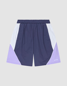 The LIVE FAST DIE YOUNG Basic Nylon Trackshorts feature a regular fit, elastic waistband, color-block design in navy, white, and light purple, plus a subtle logo stitch on a plain gray background. | plain
