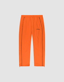 The LIVE FAST DIE YOUNG Live Fast Trackpants feature a bright orange wide-fit design with an elastic waistband, black vertical leg piping, side pockets, and a reflective logo print on the left thigh, presented on a plain light gray background. | plain