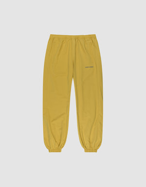 LFDY Trackpants by LIVE FAST DIE YOUNG in yellow with elastic waistband and cuffs, side pockets, and reflective LOVERBOY print on the left thigh, shown on a plain light gray background. | plain