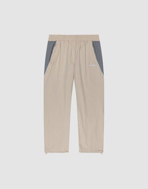 LIVE FAST DIE YOUNG Basic Nylon Trackpants in beige with grey side panels, elastic waistband, side pockets, and elasticated cuffs, displayed flat on a plain light background. | plain