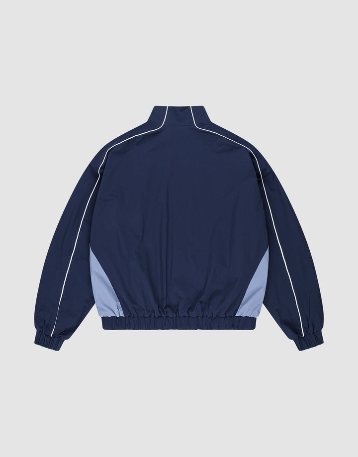 The LIVE FAST DIE YOUNG Basic Nylon Trackjacket, shown from the back on a plain light background, features navy blue nylon, light blue side panels, white sleeve piping, elastic cuffs, a high collar with zipper, and a regular fit.