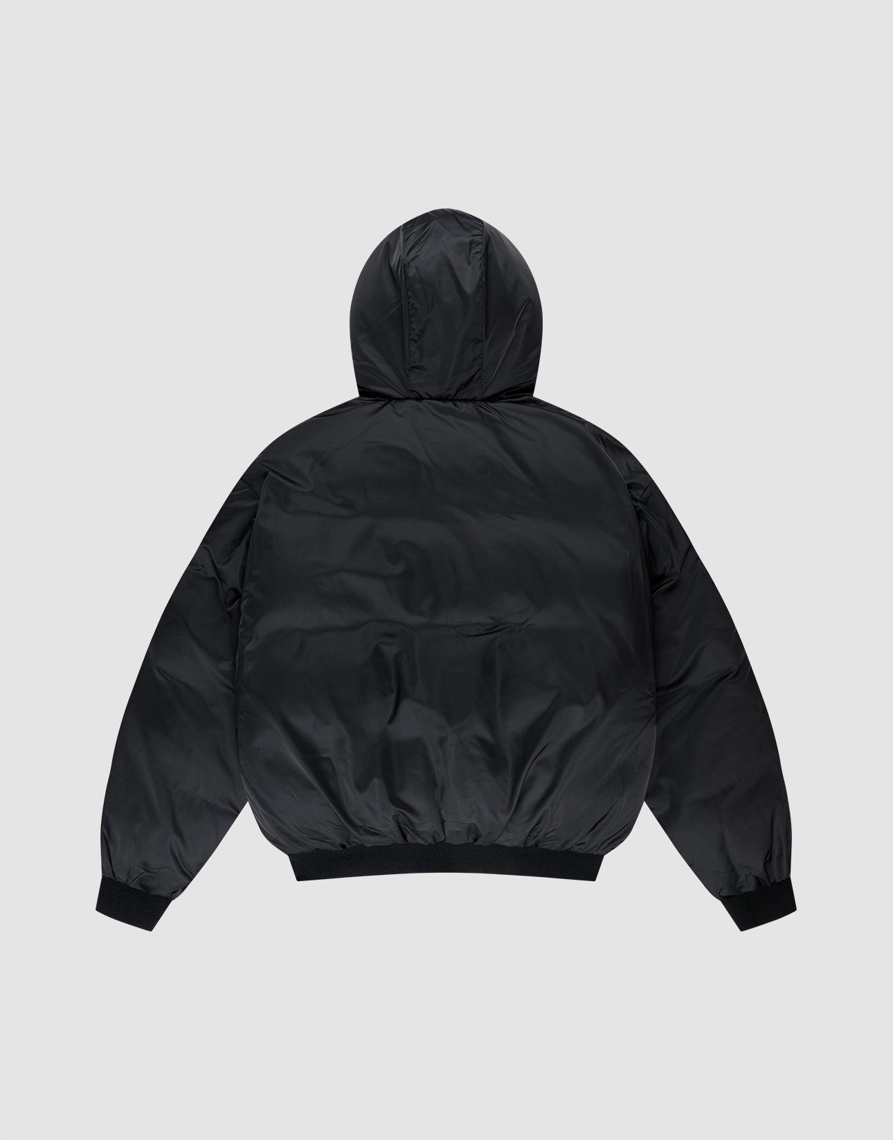 The LFDY Winter Bomber Jacket by LIVE FAST DIE YOUNG is a black puffer with Oversize Fit and hood with drawstrings, shown from the back on a light gray background. It features long sleeves, ribbed cuffs, and a ribbed hem.