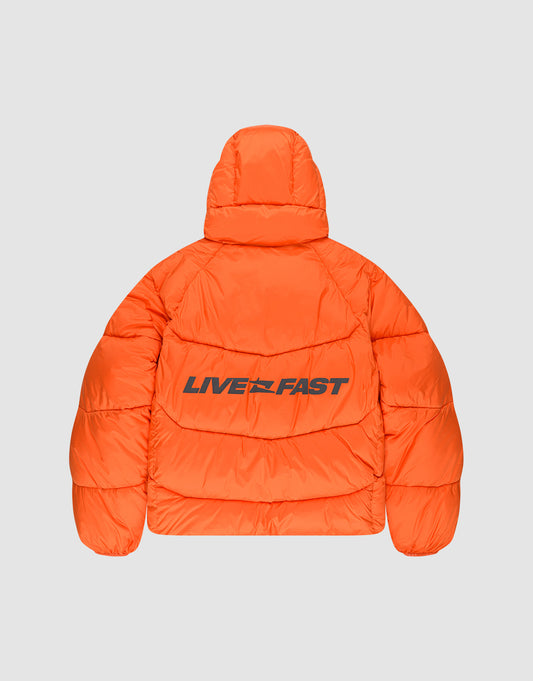 The LIVE FAST DIE YOUNG Live Fast Puffer Jacket is an oversize bright orange puffer with a hood, featuring the bold black reflective “LIVE FAST” print across the back.
