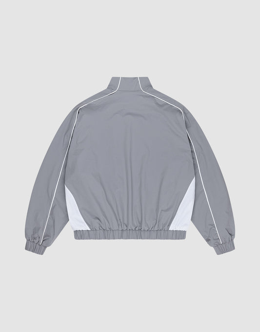 The Basic Nylon Trackjacket by LIVE FAST DIE YOUNG is a light gray Regular Fit windbreaker with white side accents and piping, shown from the back. Features a high collar, elastic cuffs and hem, plus subtle Logo-Stick detailing.
