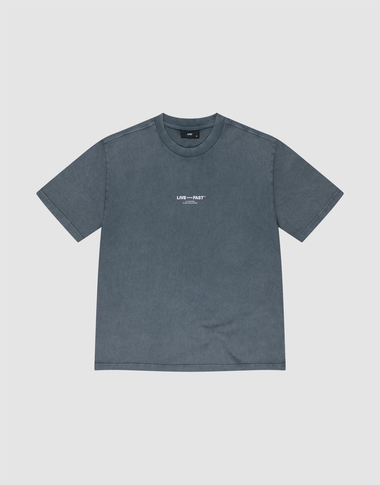 The It's Vulgar Tee by LIVE FAST DIE YOUNG is an oversize, short-sleeved, faded blue-gray T-shirt made of 100% Baumwolle, featuring small white "LIVE---FAST" text on the chest and shown laid flat on a light background.