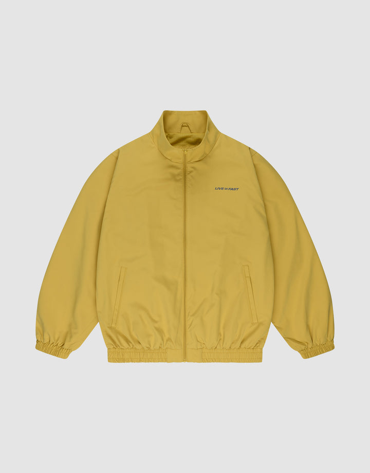 The LFDY Trackjacket by LIVE FAST DIE YOUNG is a yellow zip-up with an oversized fit, high collar, elastic cuffs and hem, two front pockets, and “LINE UM ART” text near the left shoulder on a plain light background. | plain