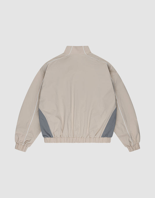 The LIVE FAST DIE YOUNG Basic Nylon Trackjacket in beige features a high collar, long sleeves with elastic cuffs, grey side panels, white piping, an elastic waistband, and a Reißverschluss. Regular fit offers versatile style and comfort.