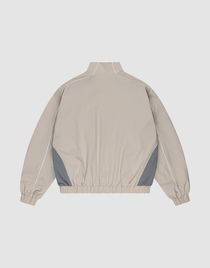 The LIVE FAST DIE YOUNG Basic Nylon Trackjacket in beige features a high collar, long sleeves with elastic cuffs, grey side panels, white piping, an elastic waistband, and a Reißverschluss. Regular fit offers versatile style and comfort.