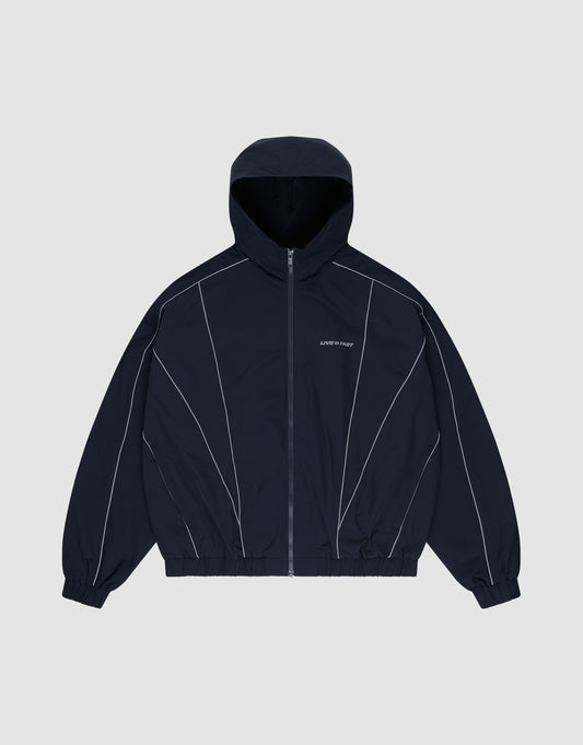 The LIVE FAST DIE YOUNG Live Fast Trackjacket, a navy blue nylon regular fit jacket with front zipper, elastic cuffs and hem, white piping, and reflective "LIPHOP" on the left chest, is displayed flat on a light gray background. | plain