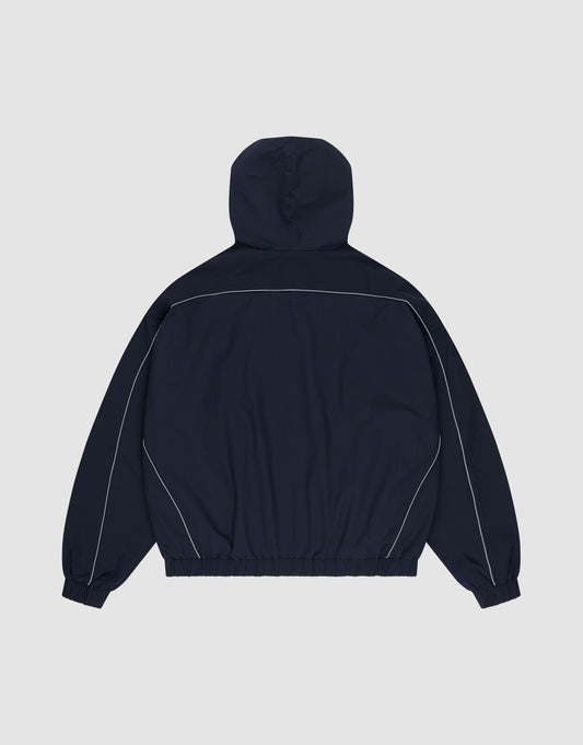 The Live Fast Trackjacket by LIVE FAST DIE YOUNG is a navy blue nylon jacket, shown from the back with white piping on shoulders and sleeves, reflective print details, plus elastic cuffs and waistband for a comfy regular fit.