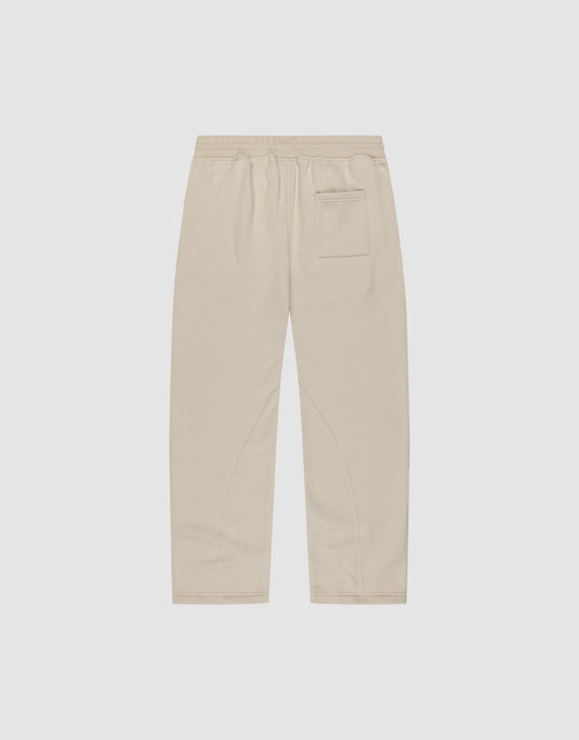Die LFDY Pleated Jogger von LIVE FAST DIE YOUNG ist eine beigefarbene Hose mit weitem Schnitt, Elastikbund und einer Gesäßtasche, flach auf weißem Hintergrund präsentiert.
