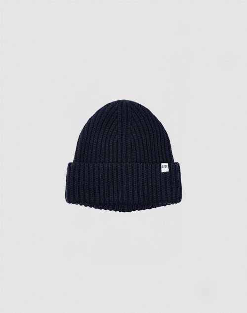 The LIVE FAST DIE YOUNG Rib Knit Beanie in navy blue, made from soft polyacryl with a folded brim and small white side tag, is shown on a plain light gray background.
