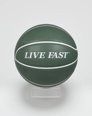 A dark green Live Fast Basketball by LIVE FAST DIE YOUNG, featuring bold white LIVE FAST lettering and white stripes, displayed on a clear stand against a plain white background.