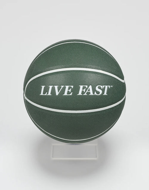 A dark green Live Fast Basketball by LIVE FAST DIE YOUNG, featuring bold white LIVE FAST lettering and white stripes, displayed on a clear stand against a plain white background.