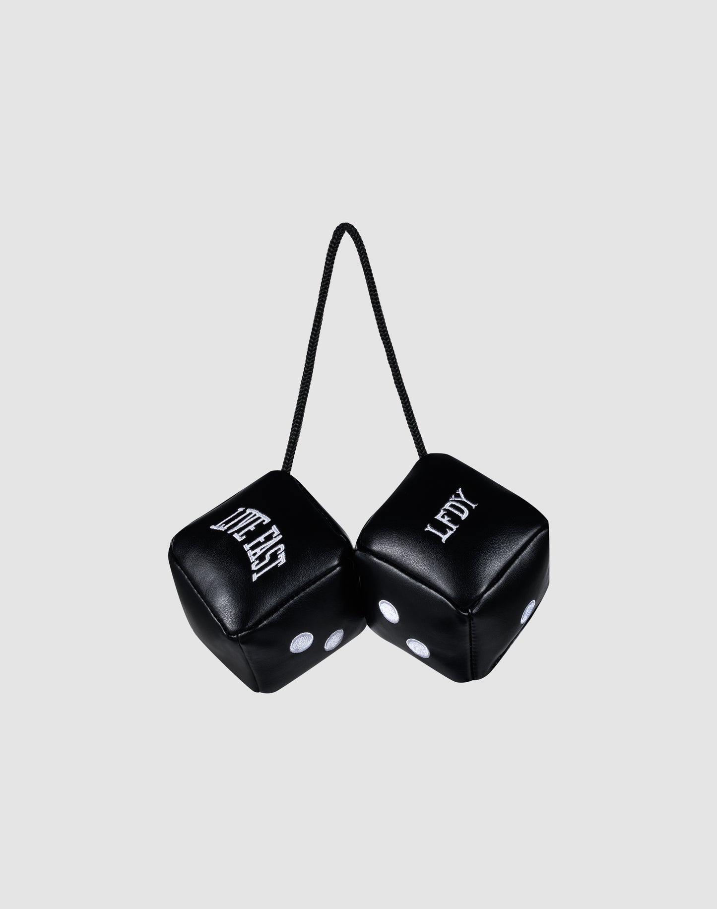Two black LFDY Leather Car Dice by LIVE FAST DIE YOUNG, connected by a black string, hang from your rearview mirror. Both display "LEFTY" with white dots and lettering against a plain light gray background.