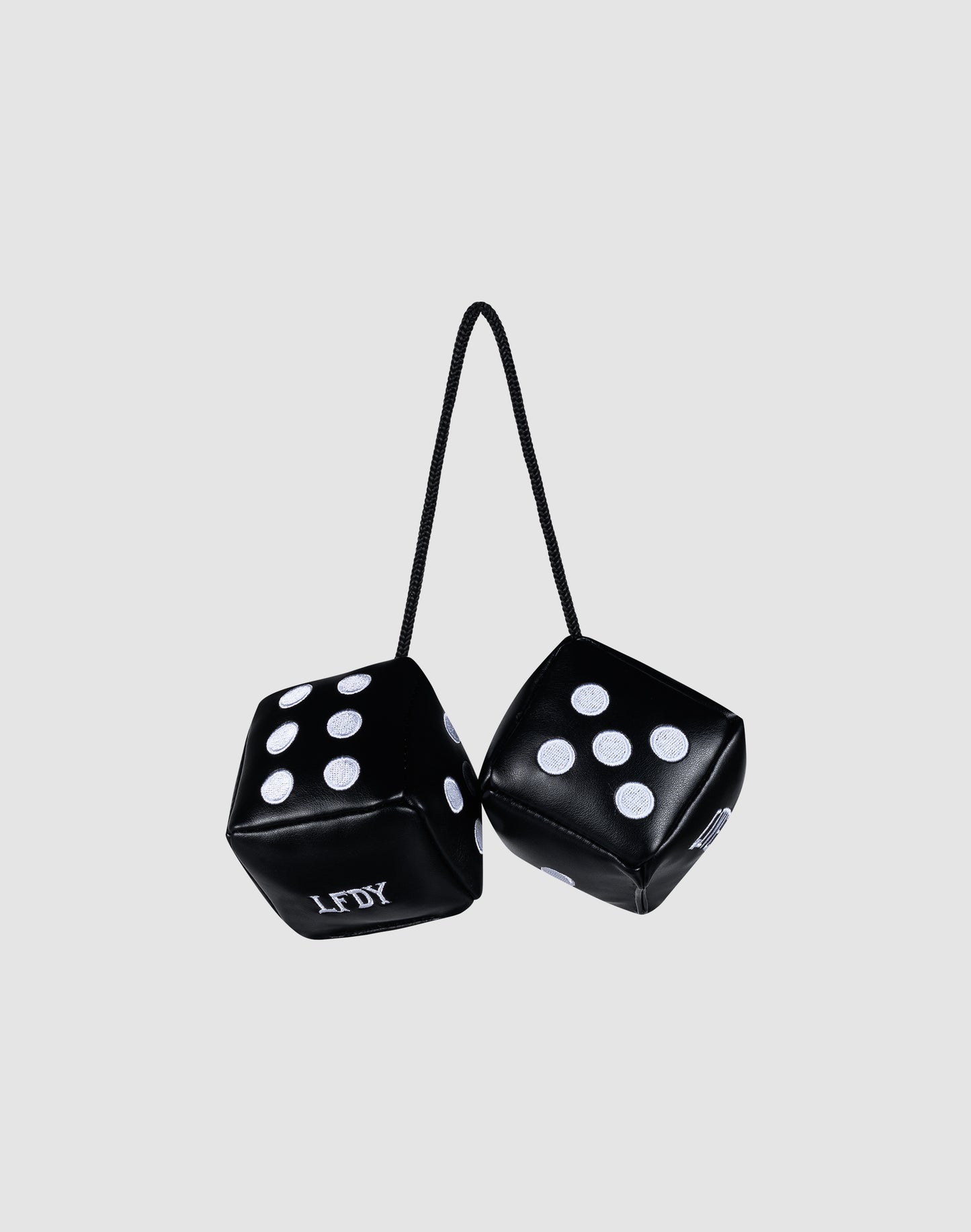 The LFDY Leather Car Dice by LIVE FAST DIE YOUNG are black fuzzy dice with white dots, joined by a black string and ideal for your rearview mirror. One die features embroidered LFDY letters, shown on a plain gray background.