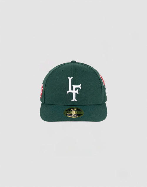 The LFDY x NEW ERA 59FIFTY Low Profile by LIVE FAST DIE YOUNG is a dark green fitted cap with a flat brim, large white LF logo on the front, side patches, and a gold sticker on the brim.