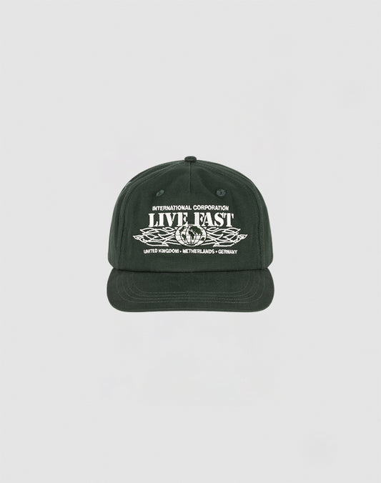 The Live Fast Corporation Cap by LIVE FAST DIE YOUNG is a black 5-panel cap with white INTERNATIONAL CORPORATION LIVE FAST text above wings and country names below, featuring a Multi-Logo design on a plain light background.