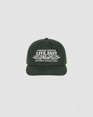 The Live Fast Corporation Cap by LIVE FAST DIE YOUNG is a black 5-panel cap with white INTERNATIONAL CORPORATION LIVE FAST text above wings and country names below, featuring a Multi-Logo design on a plain light background.