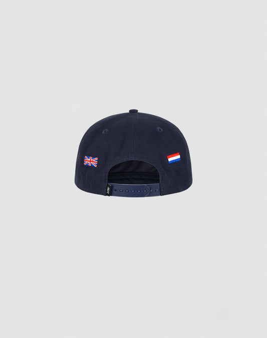 A navy blue Live Fast Corporation Cap by LIVE FAST DIE YOUNG, shown from the back with an adjustable strap. The Multi-Logo design features UK and Russian flag-labels on the sides against a plain light gray background.
